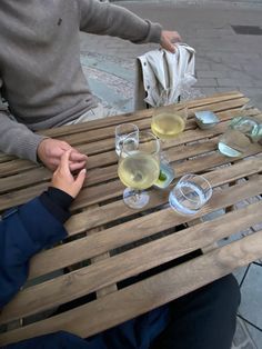 two people sitting at a wooden table with wine glasses