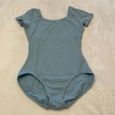 a woman's bodysuit laying on top of a white sheeted bed with no sheets