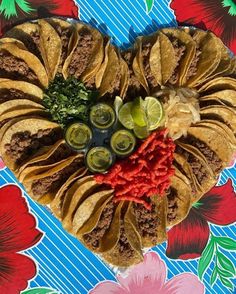 a heart shaped tortilla with salsa, limes and other toppings on it