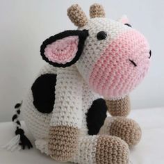 a crocheted cow sitting on the ground with it's eyes closed and tongue out