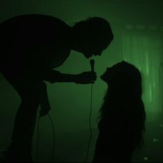 two people in the dark with one holding a microphone