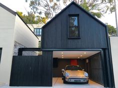 a car is parked in front of a black garage with an open door and windows