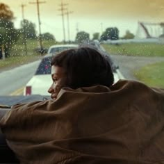 a man sitting in the passenger seat of a car with his back to the camera