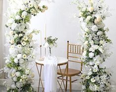 an arch decorated with white flowers and greenery stands in front of a table set for a formal dinner