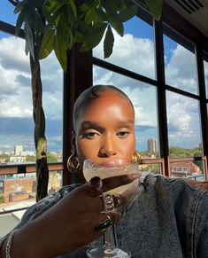 a woman holding a wine glass in front of her face and looking at the camera