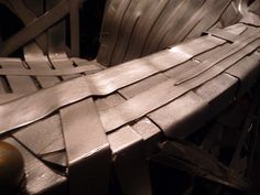 a bench made out of metal strips and some other things in the back ground with sunlight shining on it