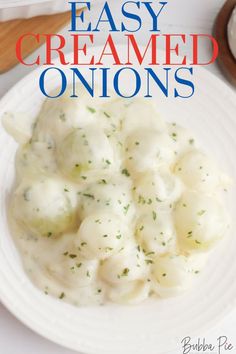 a white plate topped with dumplings covered in cream sauce and garnished with parsley