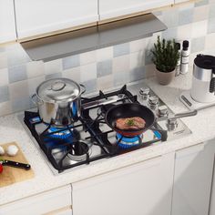 a stove top with pots and pans on the burners in a white kitchen