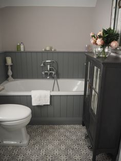 a white toilet sitting next to a bath tub in a bathroom on top of a tiled floor