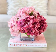 a vase filled with pink flowers sitting on top of a book