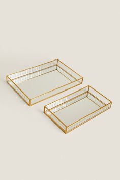 two rectangular trays with gold trim on each side, one is empty and the other has