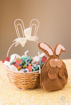 a basket filled with candies next to an easter bunny stuffed animal sitting on top of a table