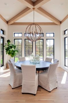 a dining room table with white chairs and a chandelier hanging from the ceiling