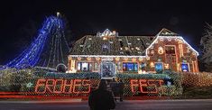 a large house covered in christmas lights at night with a person walking by the front door