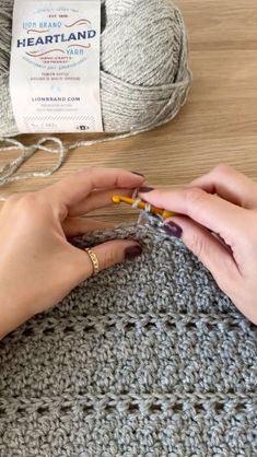 a woman is knitting on the table with yarn