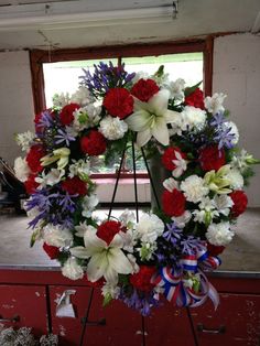 a wreath with red, white and blue flowers on it in front of a window