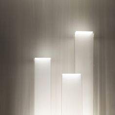 three rectangular lights are lit up in a room with white walls and flooring on either side