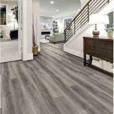 a living room with grey wood flooring and white staircase leading up to the second floor