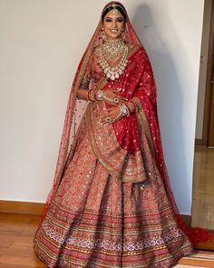 a woman in a red and gold bridal gown posing for the camera with her hands on her hips