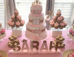 a pink table topped with lots of cakes and cupcakes