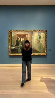 a woman standing in front of a painting on display at an art museum with her arms crossed