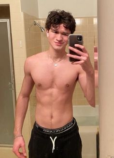 a shirtless young man taking a selfie in the bathroom with his cell phone