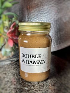 a glass jar filled with peanut butter sitting on top of a counter next to a potted plant