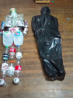 there are many plastic bottles on the floor next to a black bag and a sleeping bag