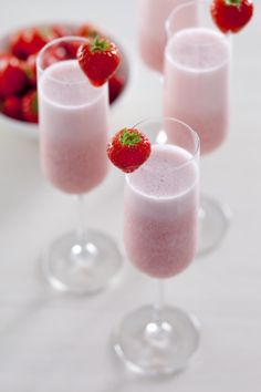 three glasses filled with liquid and topped with strawberries