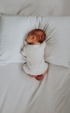 a baby laying on top of a white pillow