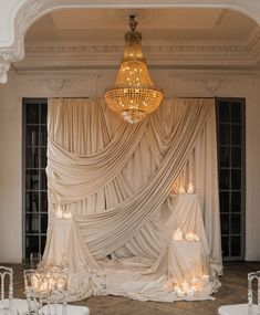 an elegant wedding setup with candles and draping on the wall, chandelier