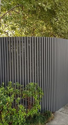 a fire hydrant sitting on the side of a sidewalk next to a tall fence