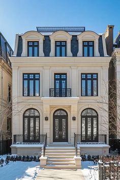 a large white house with lots of windows and steps leading up to the front door