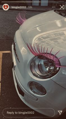 the front end of a white car with pink eyelashes on it