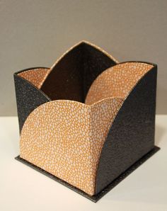 an orange and black paper holder sitting on top of a white table next to a gray wall