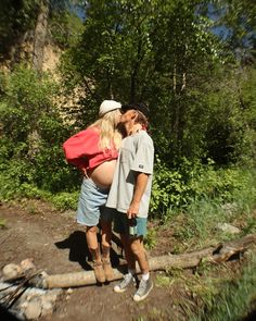 a man and woman are kissing on the side of a road in front of some trees