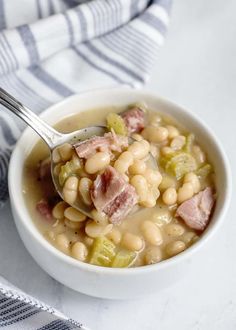 a white bowl filled with beans and ham