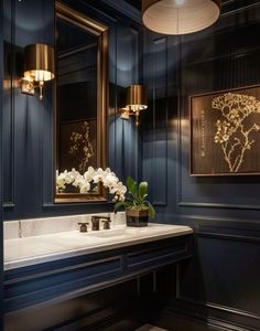 a bathroom with blue walls and white flowers on the sink counter, along with two gold framed mirrors