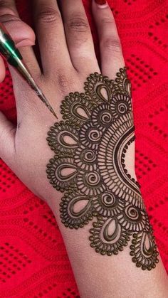 a woman's hand with henna on it and a pen in the other hand