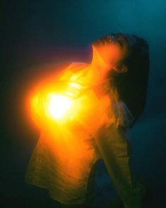 a woman holding a light up in the air with her eyes closed and head tilted to the side