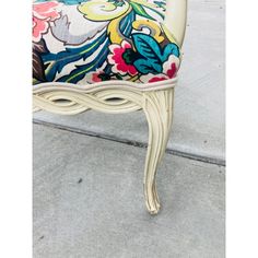 an ornately decorated chair sitting on the side of a sidewalk with concrete flooring