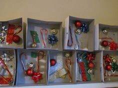 twelve christmas ornaments are arranged in boxes on a shelf with ribbons, bows and bells