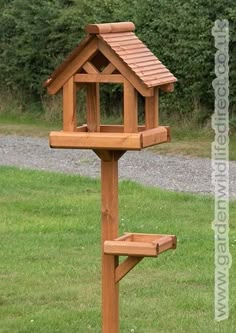 a wooden bird house in the grass