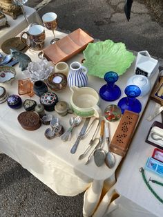 a table topped with lots of different types of dishes and utensils on top of a white table cloth