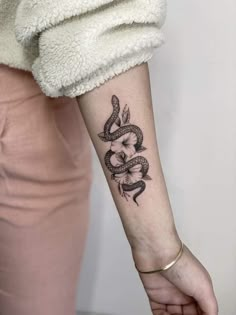 a woman's arm with a snake and flower tattoo on the left side of her arm