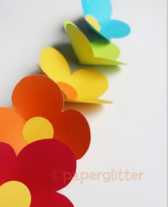 colorful paper flowers are lined up on a white surface