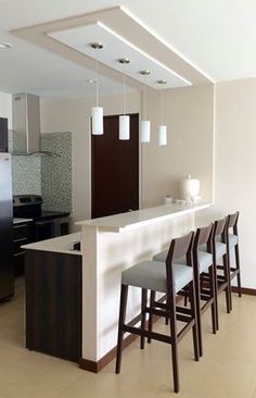 an empty kitchen with bar stools next to it