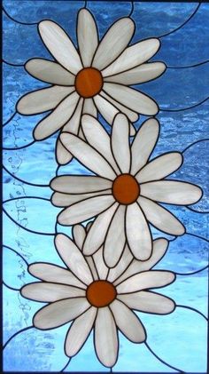 three white daisies on a blue background in a stained glass window with brown centers