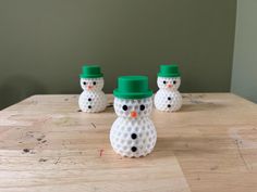 three plastic snowmen sitting on top of a wooden table