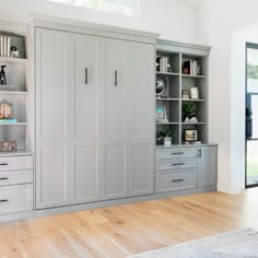 a living room filled with lots of furniture and bookshelves on top of wooden floors